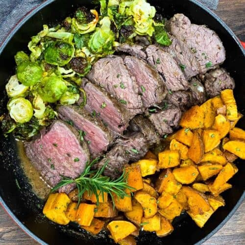 Sous vide beef tenderloine in a skillet with roasted sweet potatoes and brussels sprouts