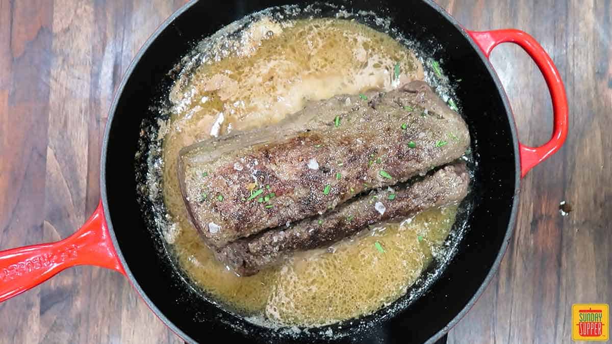 Sous vide beef tenderloin searing in a skillet with butter and garlic