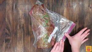 Sealing seasoned beef tenderloin in a plastic bag