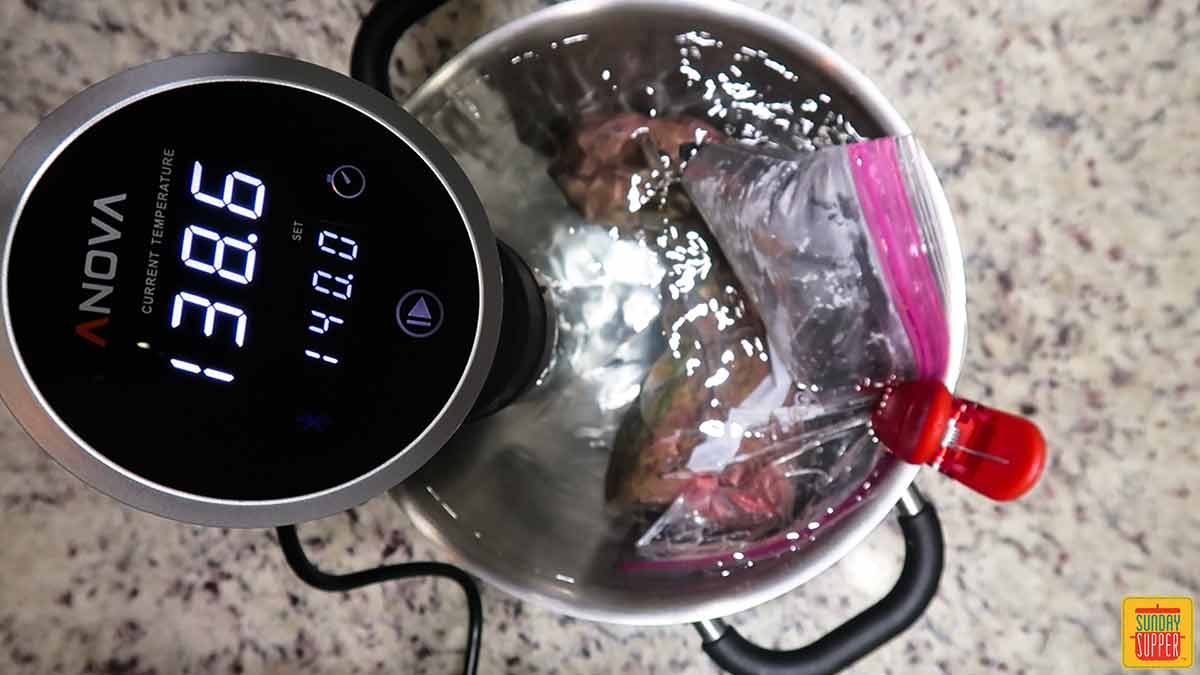 Clipping bag of beef tenderloin into a pot of water with the sous vide cooker
