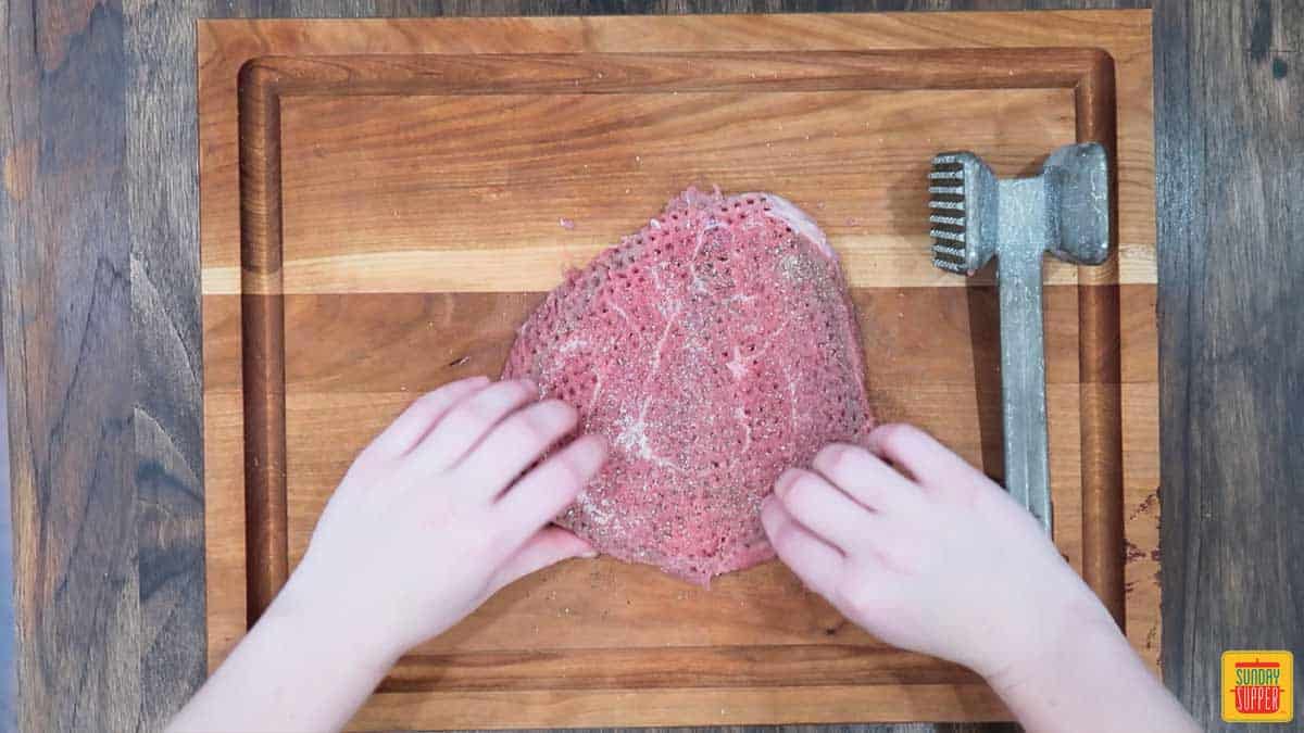 Seasoned tenderized steak on a cutting board