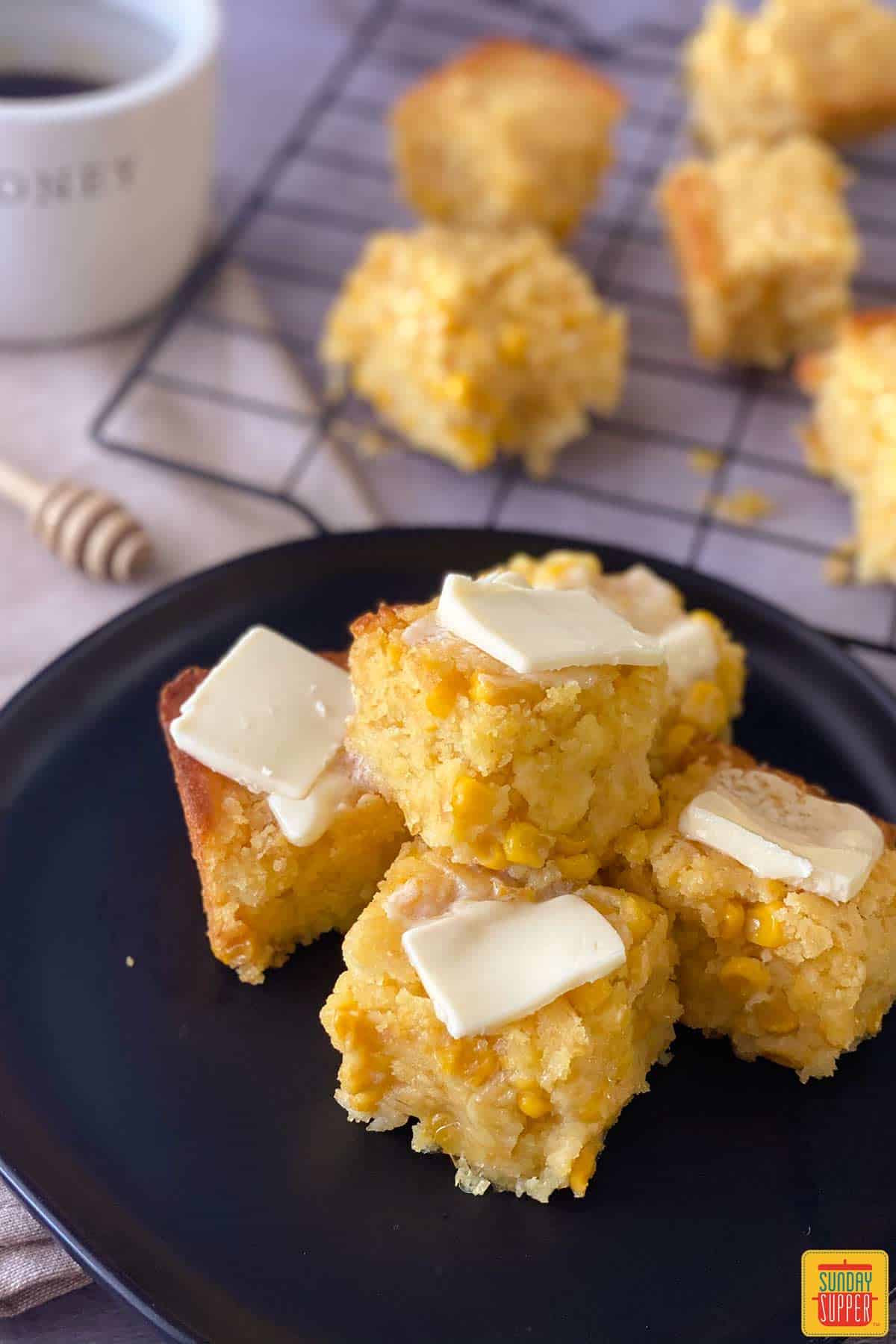 squares of creamed corn casserole on a plate with pats of butter