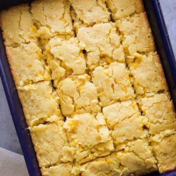 Baked creamed corn casserole cut into squares in a blue baking dish