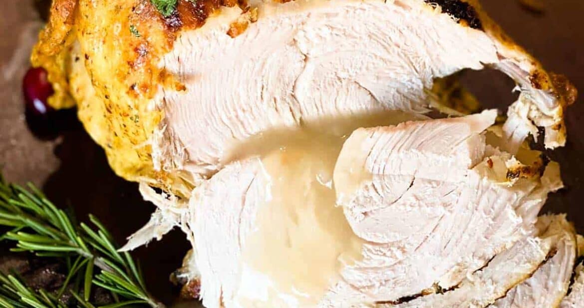 Slices of instant pot turkey breast covered with gravy and rosemary sprigs to the side