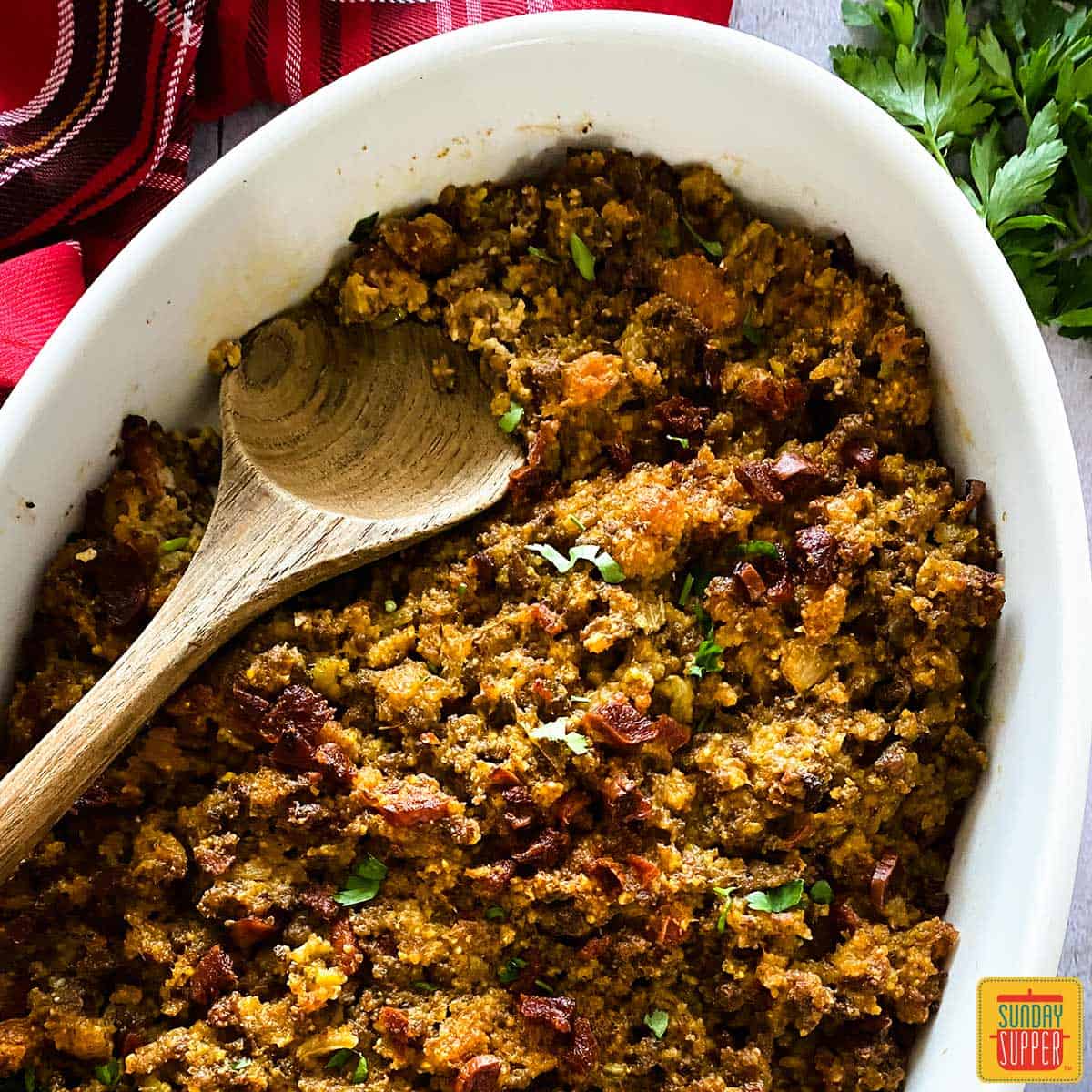 Close up of Portuguese chorizo stuffing in a white dish with a wooden spoon