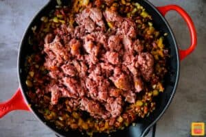 Ground beef added to the center of the pan surrounded by chorizo and vegetables