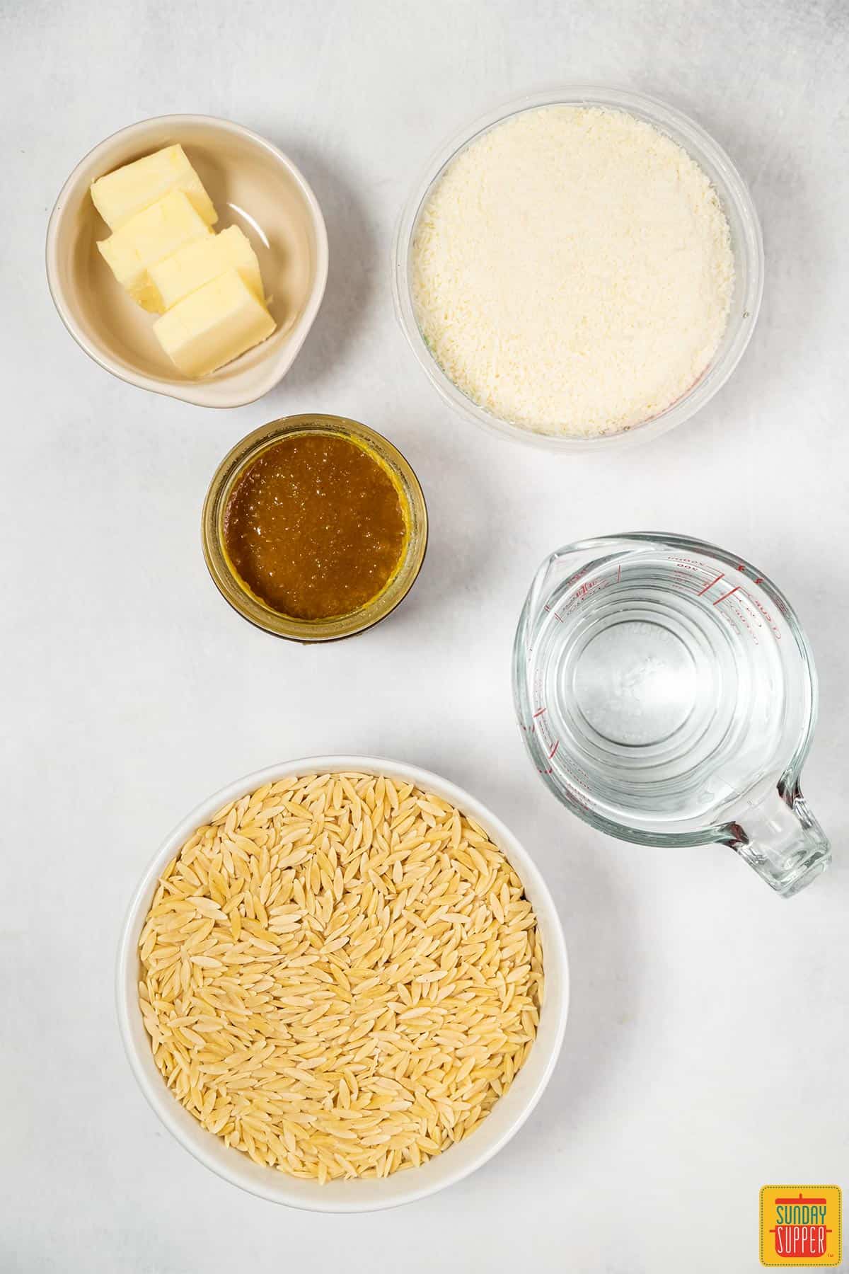cheesy orzo risotto ingredients on a white surface
