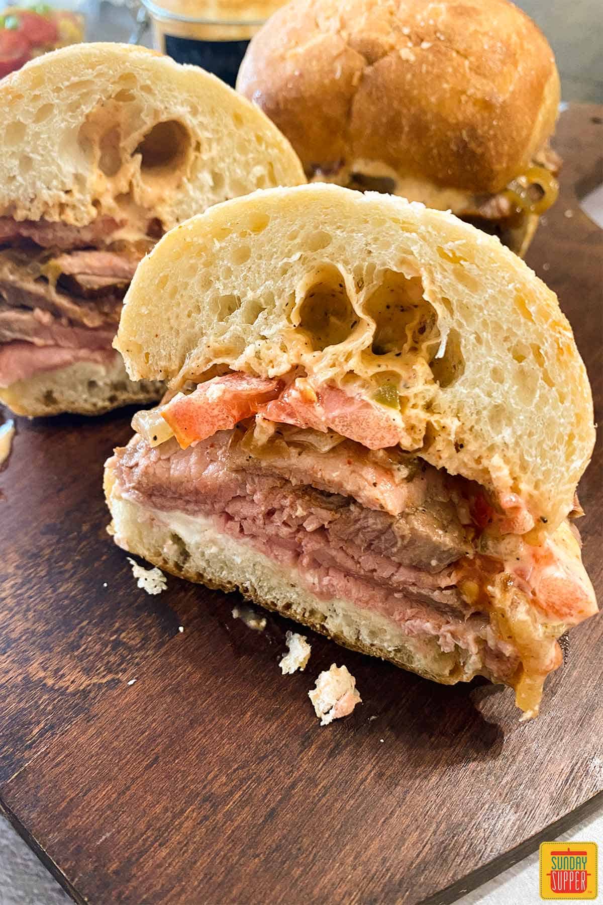 Hot roast beef sandwich sliced in half on a cutting board