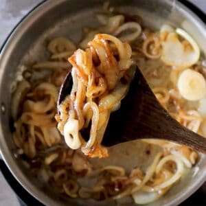 caramelized onions on a wooden spoon over a pan of onions