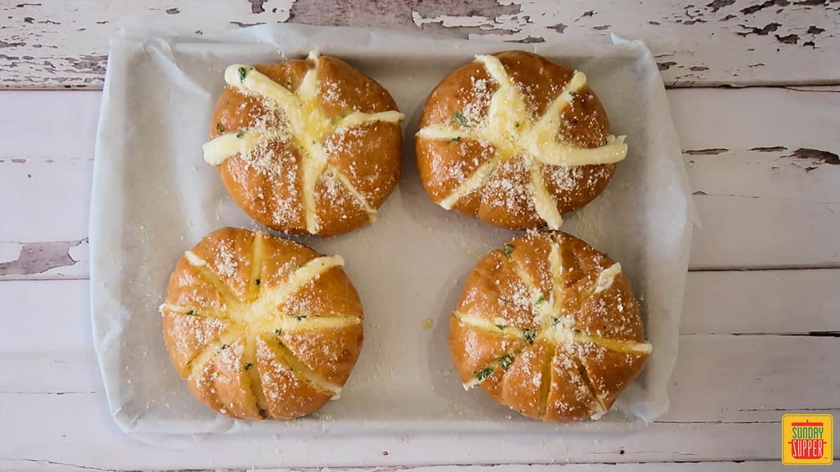 Four unbaked Korean cream cheese garlic rolls on a baking sheet