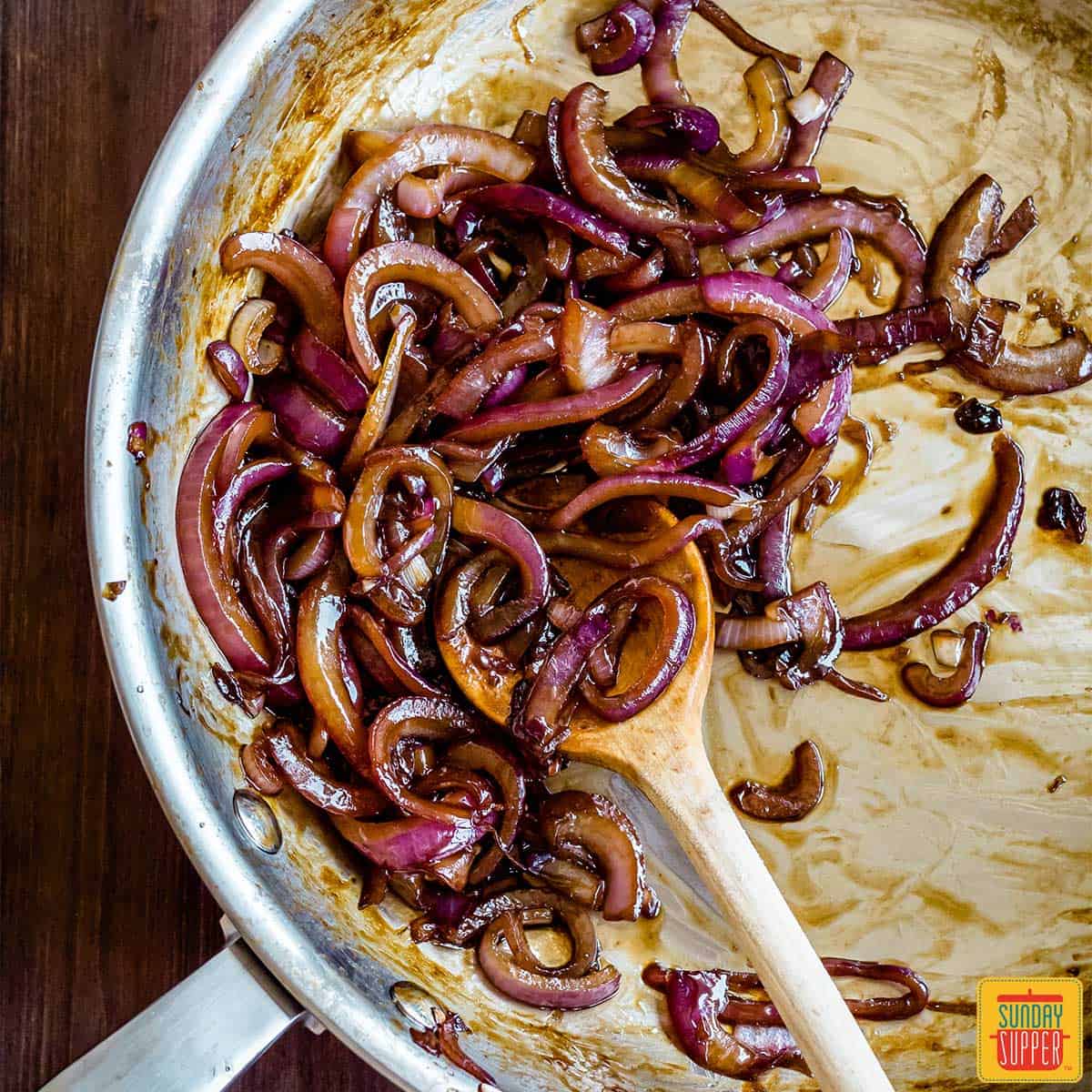 caramelized red onions in a pan with a spoon