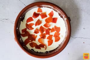 cream cheese and pepperoni on the bottom of a baking dish for pizza dip