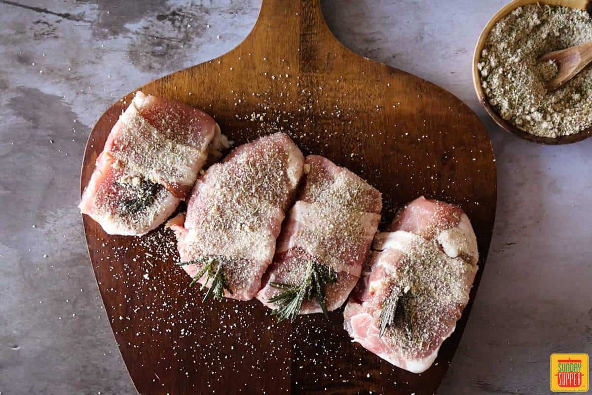 seasoned bacon-wrapped pork chops on a cutting board