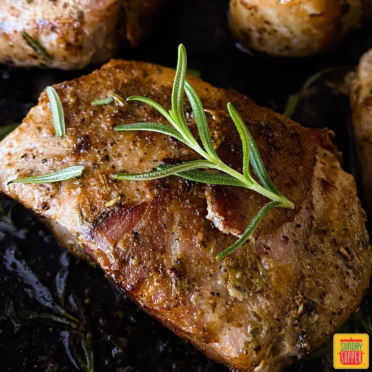 Close up of a sous vide pork chop with a sprig of fresh rosemary