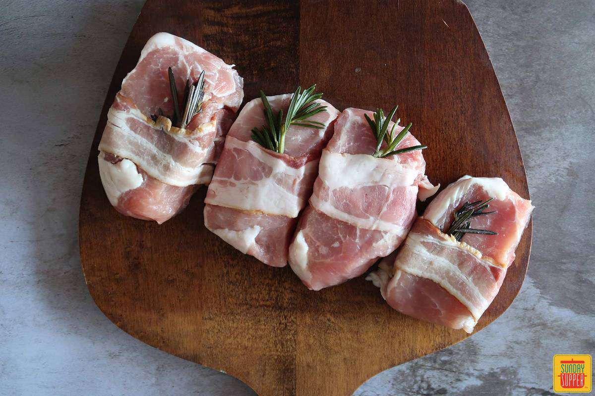 Four pork chops on a cutting board