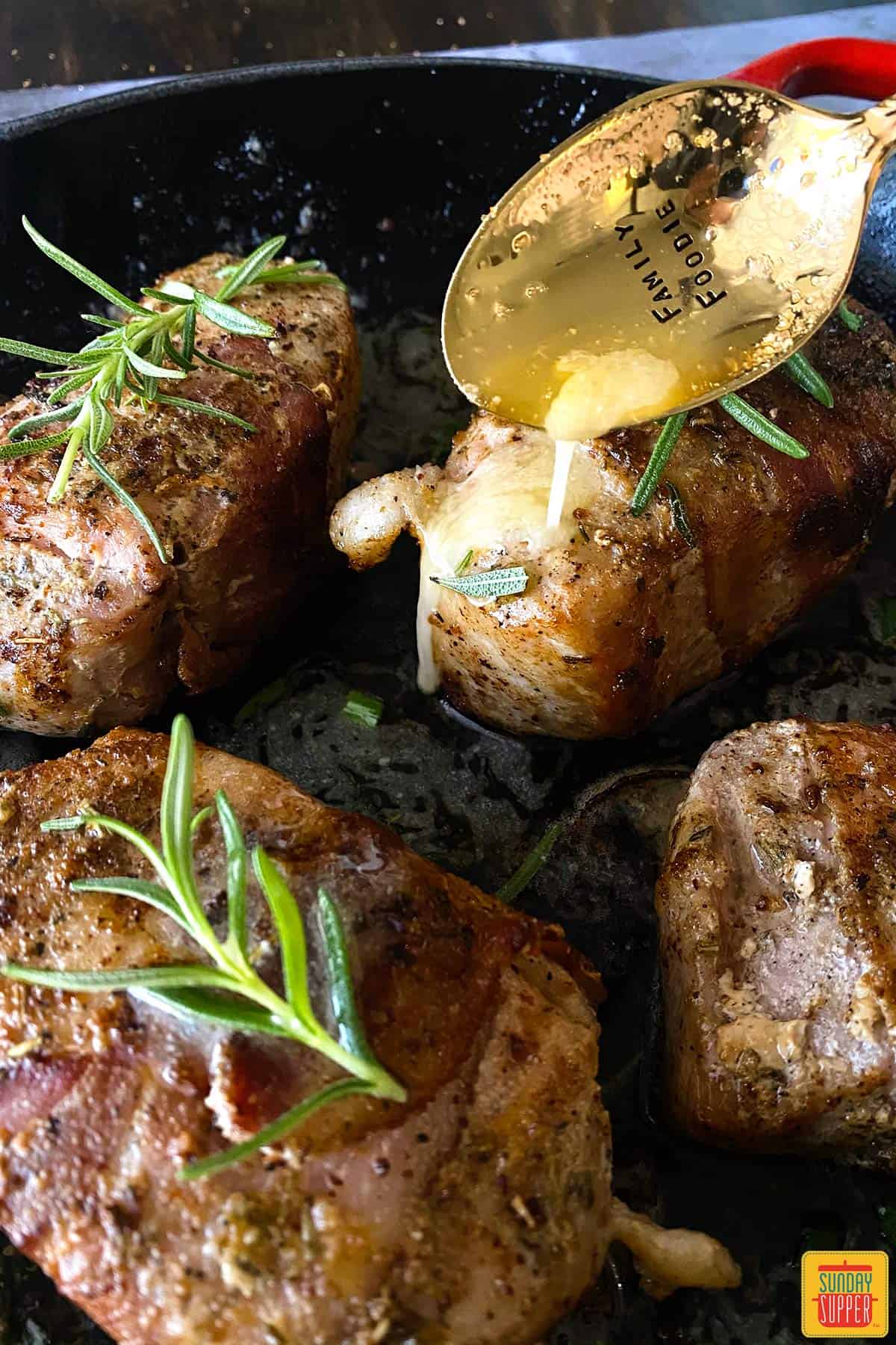 Pouring butter onto sous vide pork chops with a spoon