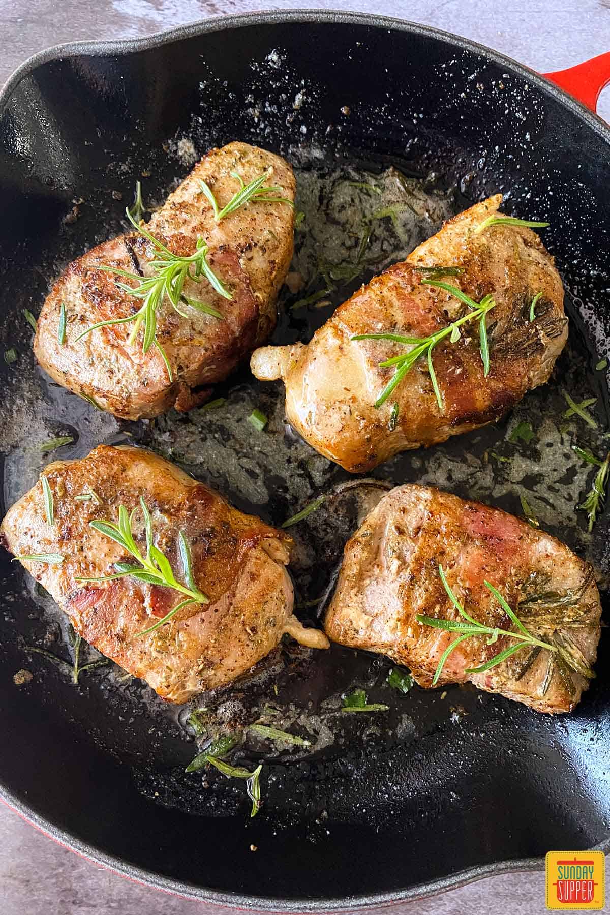 Four sous vide pork chops in a skillet