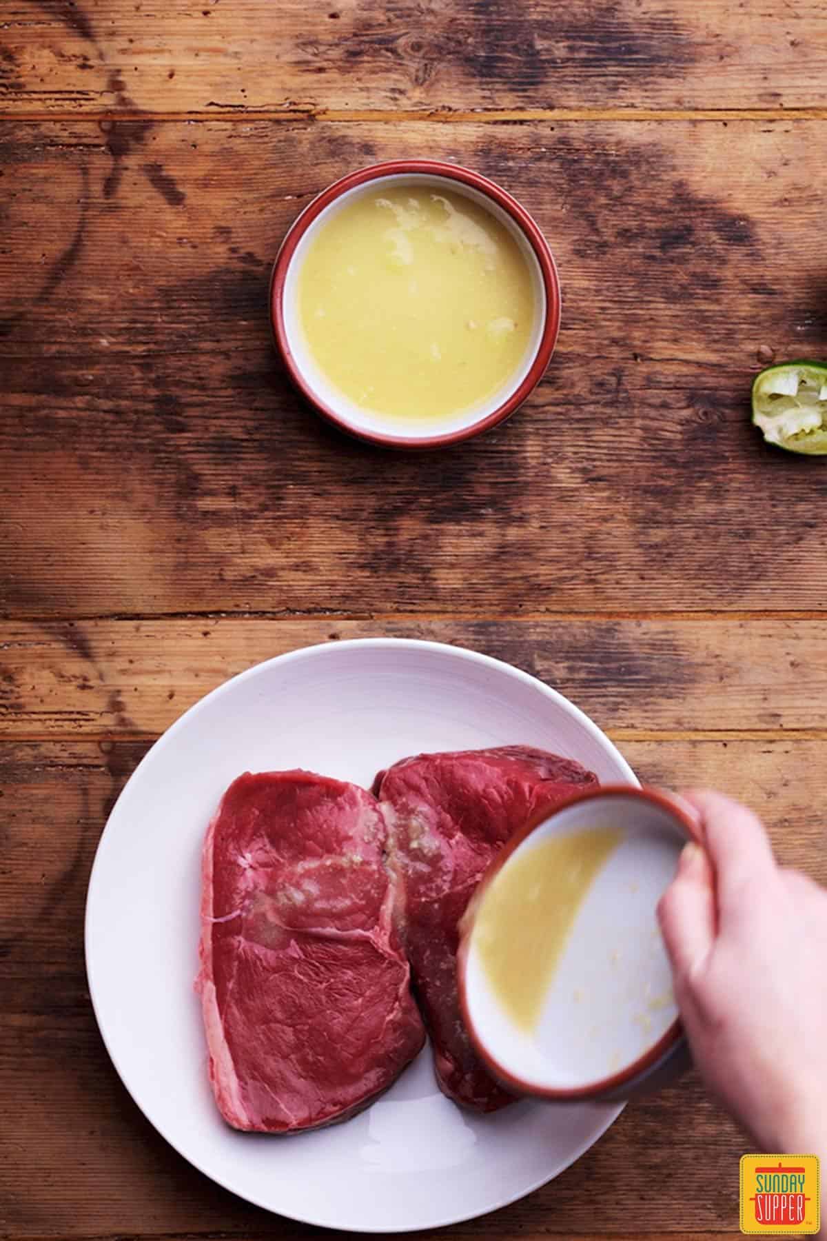 Pouring marinade over sirloin steak