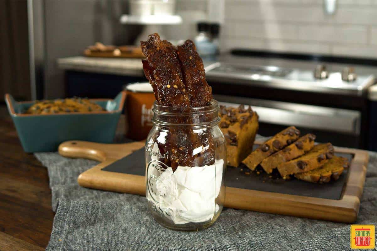 Candied bacon in a jar in front of starbucks pumpkin bread slices