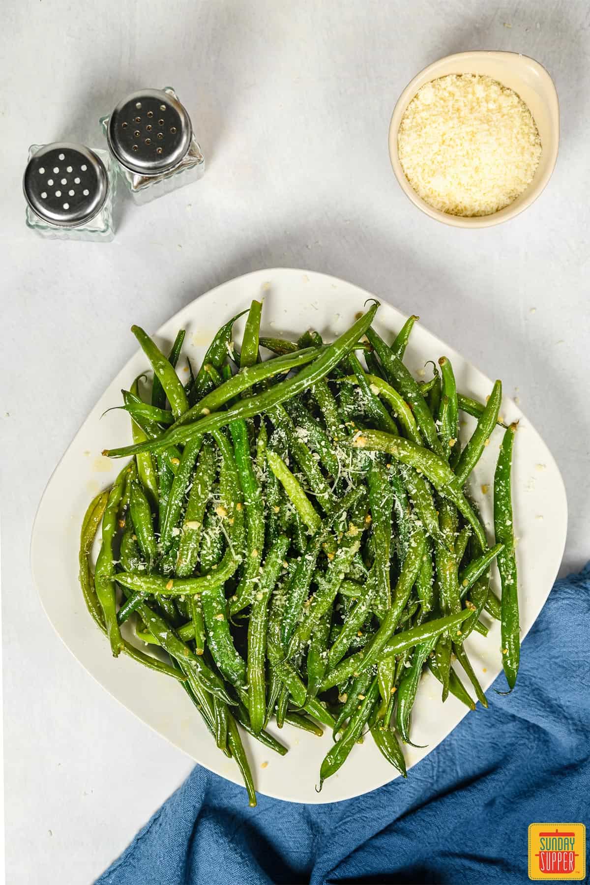 Instant pot green beans on a white plate with a salt and pepper shaker