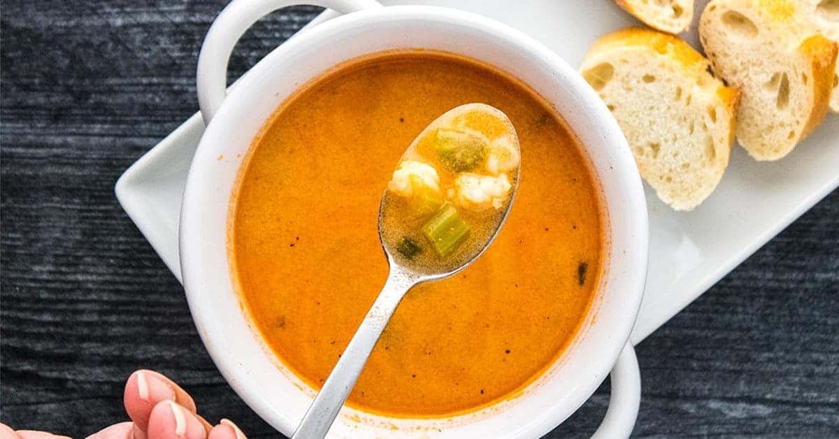 Shrimp bisque in a white bowl with a spoonful