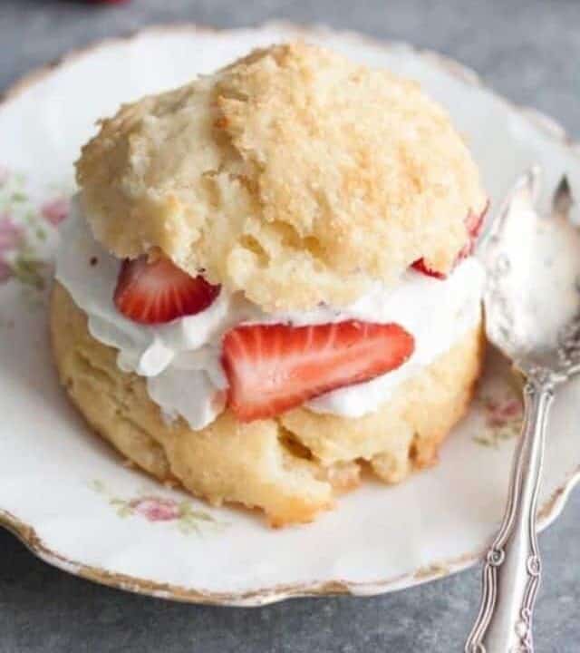Strawberry shortcake on a white plate with a metal spoon