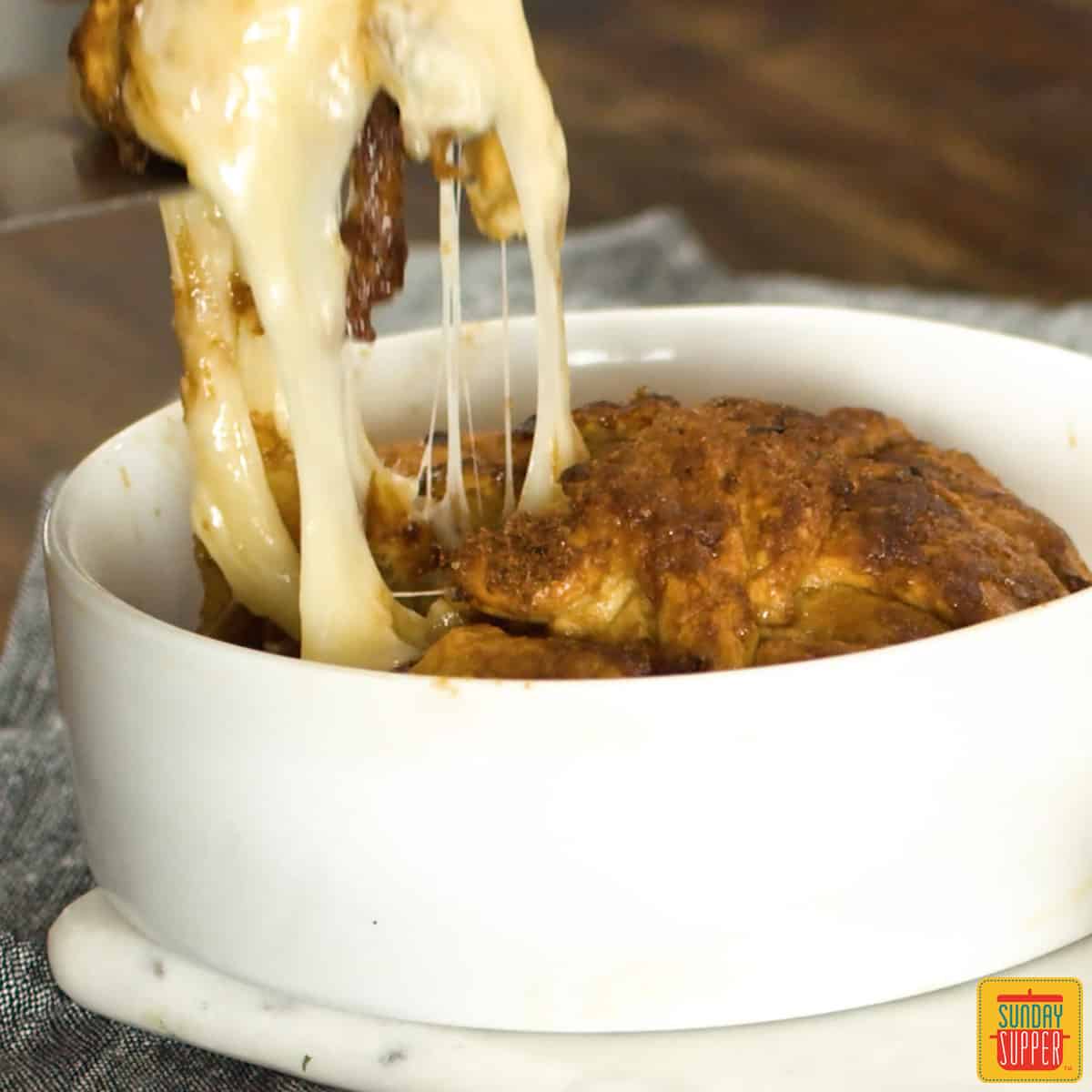 Pulling brie from white dish to show gooey cheese