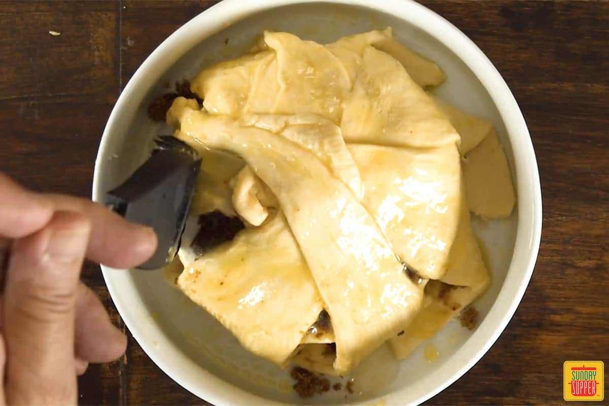 Brushing egg wash on crescent rolls over brie