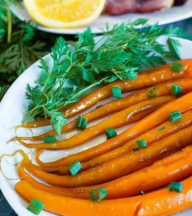Candied Carrots on a white plate with herbs