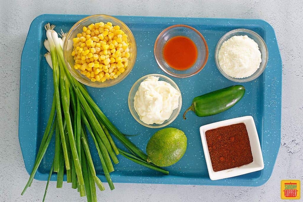 Ingredients to make street corn casserole on a blue platter