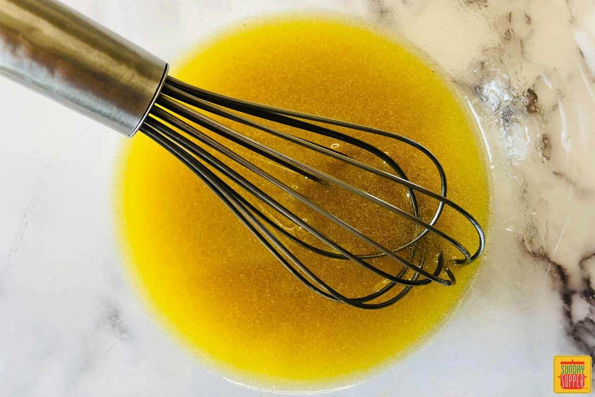 Mixing lemon vinaigrette with a whisk in a glass bowl