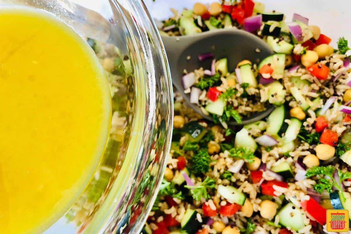 Pouring lemon vinaigrette onto quinoa salad