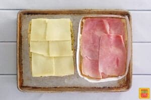 ham and cheese on slider rolls on a baking tray