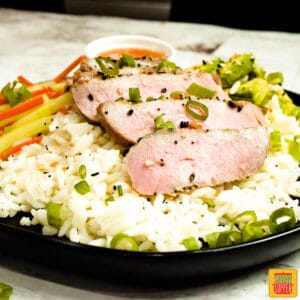 Sliced tuna steak on rice with veggies and green onions