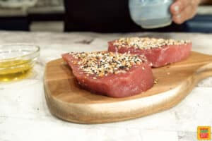 Two seasoned tuna steaks on a cutting board