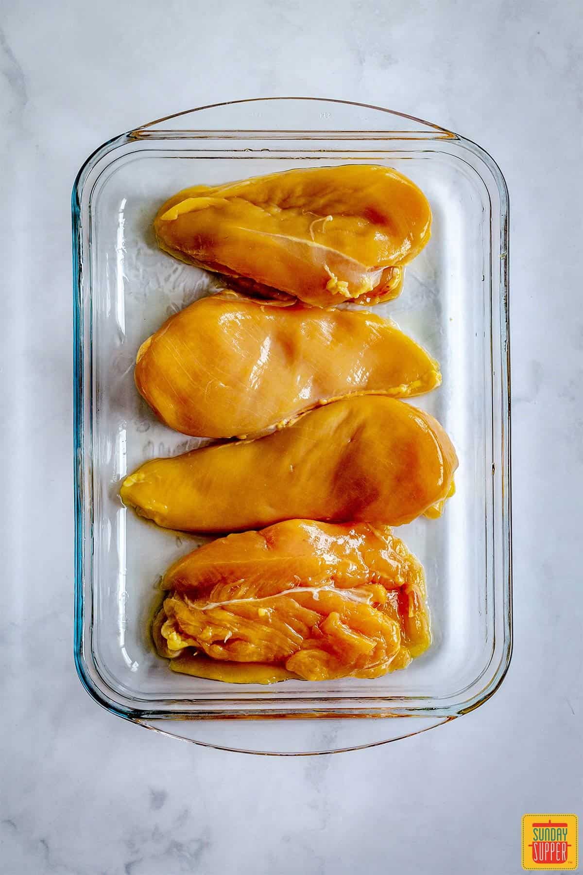 Four chicken breasts in a glass baking dish
