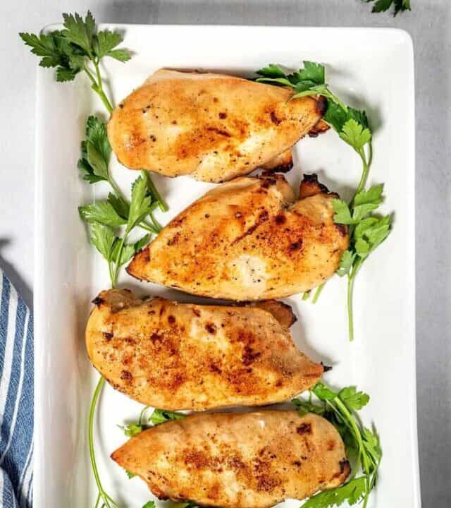 Baked chicken breasts on a white serving dish.