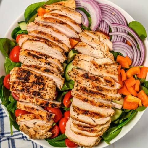 grilled chicken resting on a salad