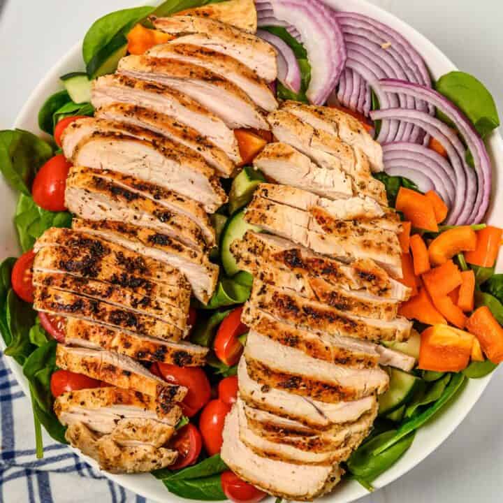 grilled chicken resting on a salad