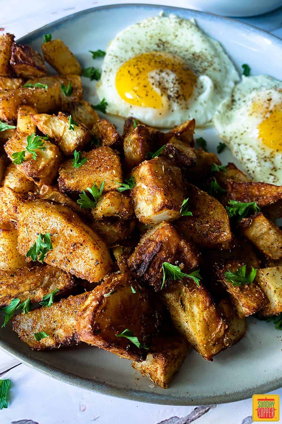 air fryer breakfast potatoes on a plate with two eggs