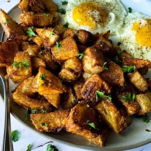 Air fryer breakfast potatoes up close on a plate with eggs