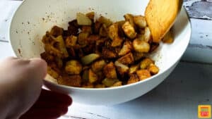 Mixing potatoes with seasoning in a bowl