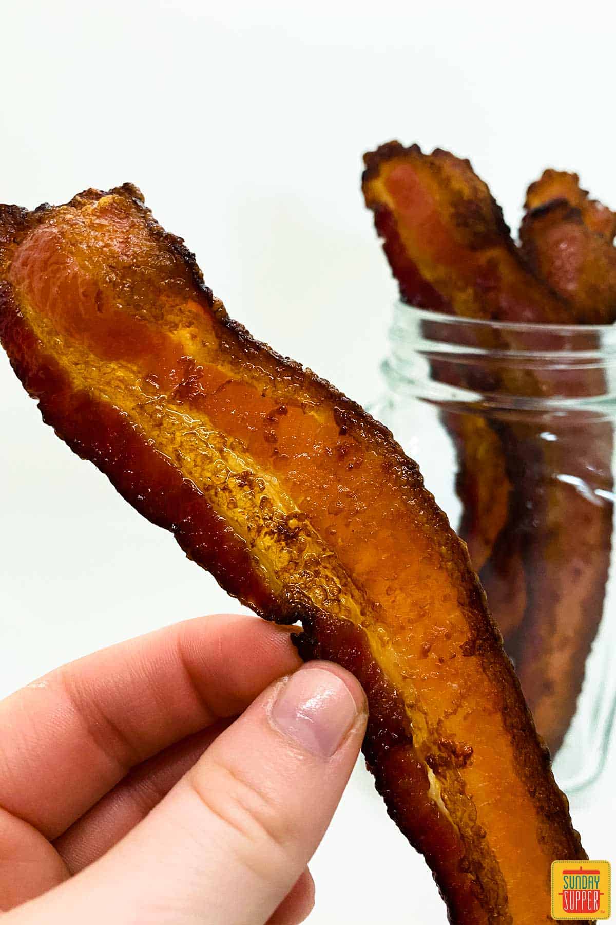 holding a strip of air fryer bacon