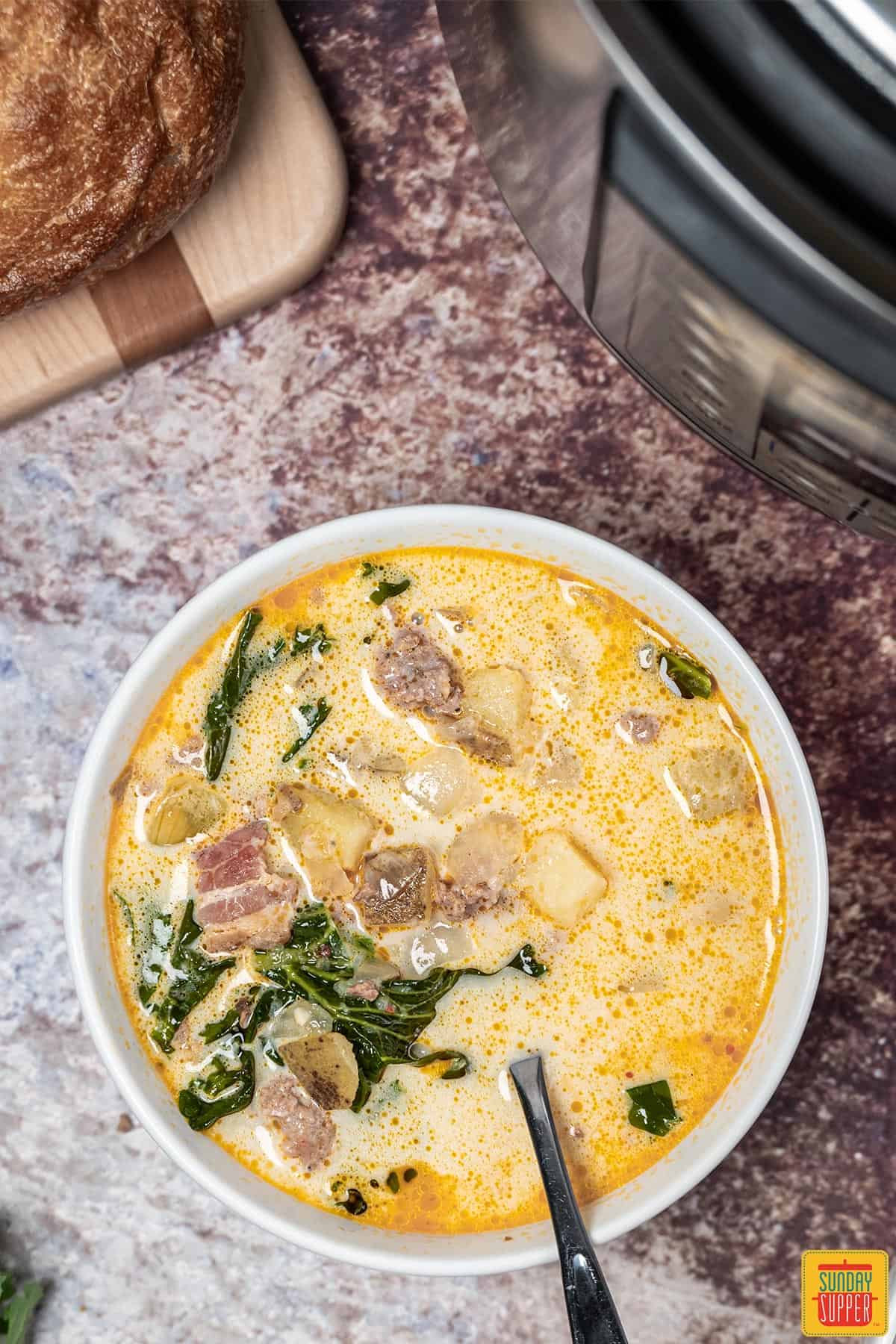 instant pot zuppa toscana with a spoon in a white bowl
