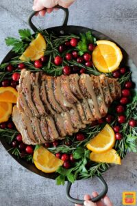 Air fryer turkey breast sliced on a round platter with citrus, cranberries, and greens