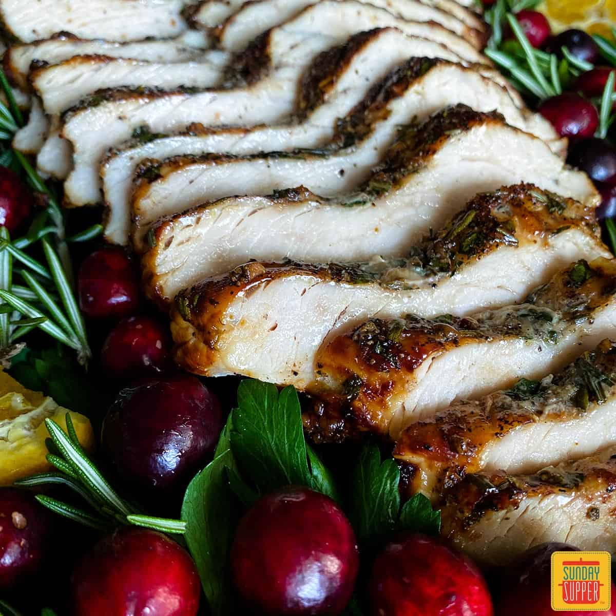close up slices of air fryer turkey breast with cranberries and greens