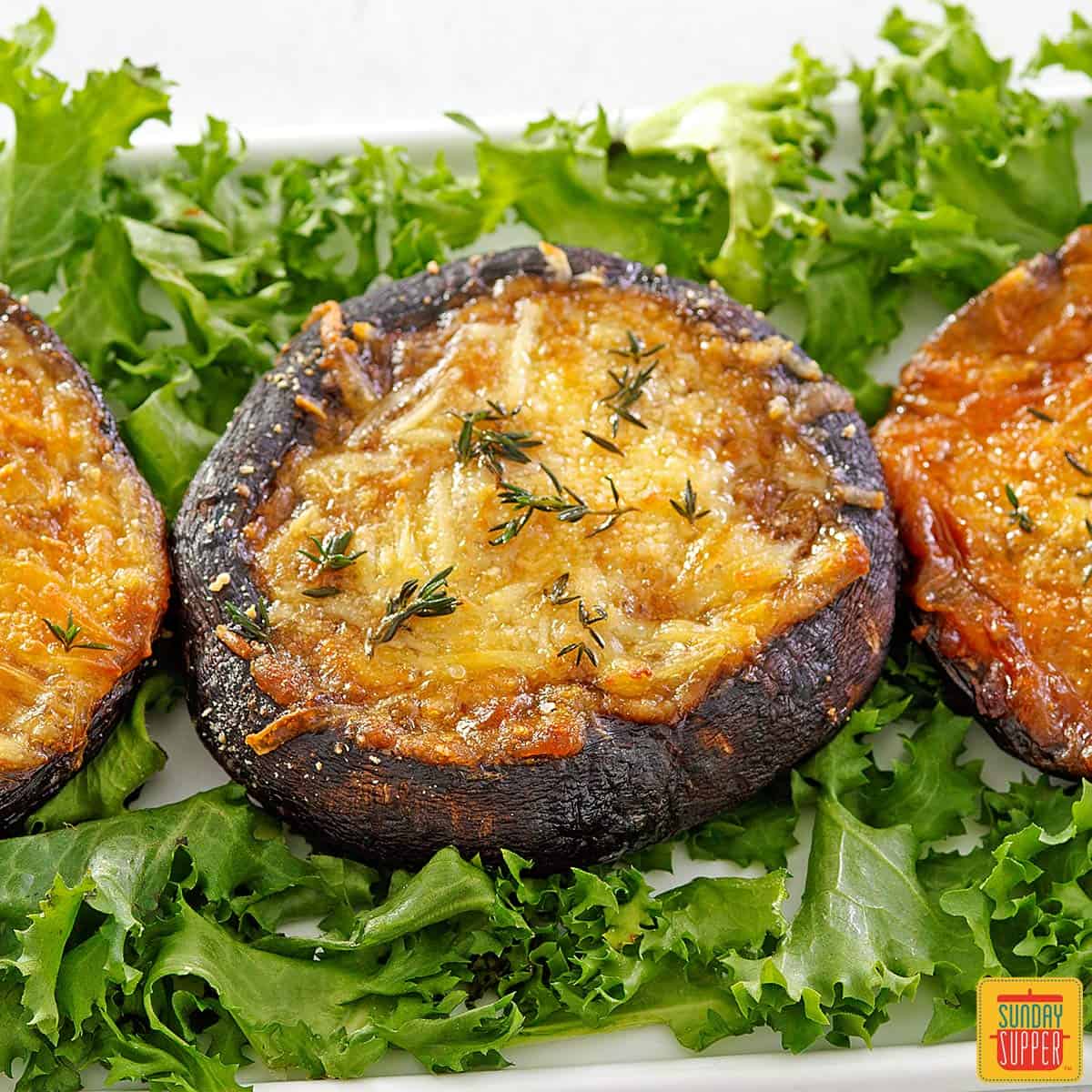 Baked portobello mushrooms stuffed with cheese surrounded by lettuce up close