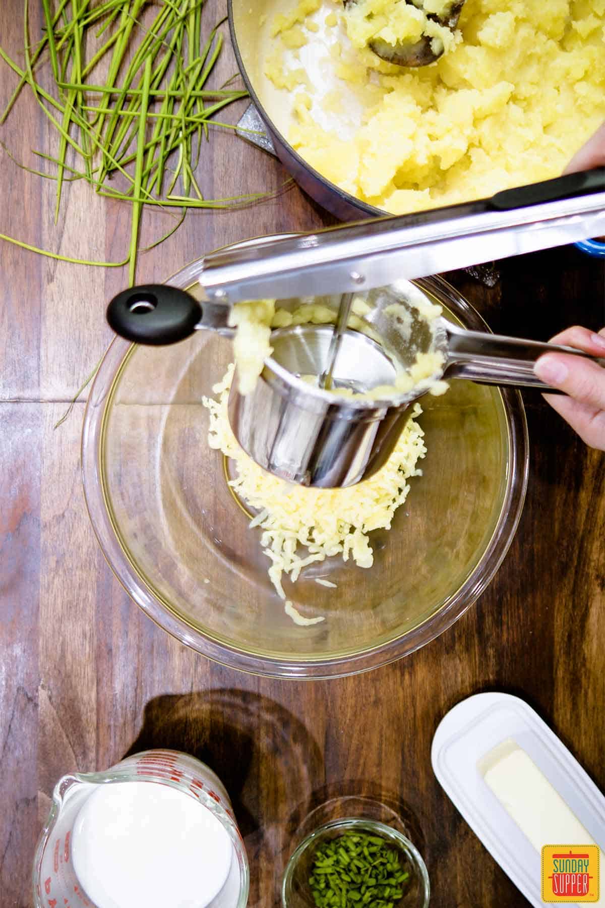 Passing potatoes through a ricer into a bowl