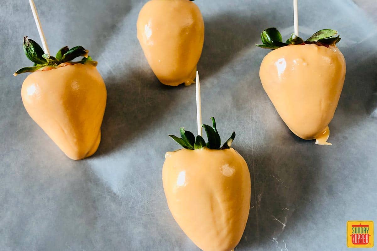 Orange chocolate covered strawberries setting on paper