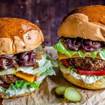 two loaded burgers up close with pickles